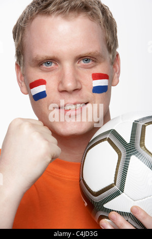 Junge männliche Fußball-Fan mit niederländischer Flagge auf Gesicht gemalt Stockfoto