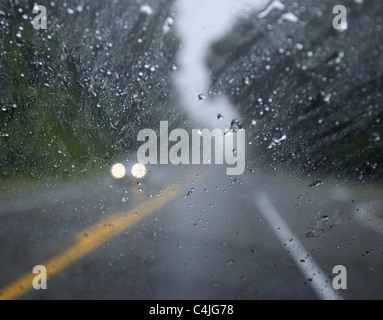 ein Auto fahren im Regen mit Scheinwerfer auf, wie von innen ein anderes Auto zu sehen. Stockfoto