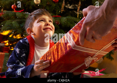 Kleiner Junge empfangen Weihnachtsgeschenk vor Baum Stockfoto