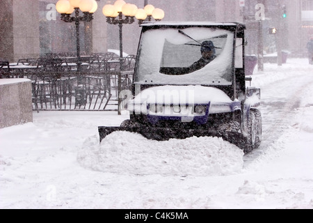 Denver, Colorado A Arbeiter in einen Traktor arbeitet in Colorado der schlimmste Schneesturm seit März 2003 von einem Bürgersteig Schneeräumung. Stockfoto