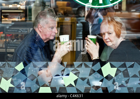 nachdenklich älteres paar gedankenverloren flüchtig durch Fenster von Starbucks Café Manhattan New York City Stockfoto