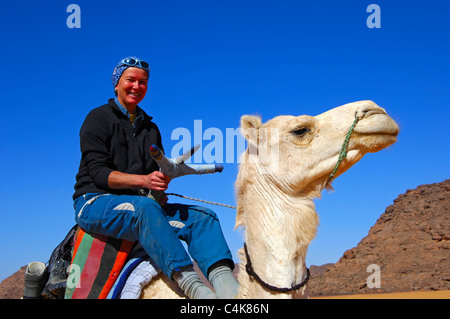 Breit grinsend touristische Reiten auf einem weißen Mehari Dromedar auf einer Wüste Ausflug, Libyen, Sahara, Nordafrika Stockfoto