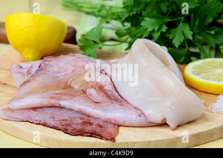 frische rohe Tintenfische auf einem Brett Küche mit Kräutern und Zitrone Stockfoto