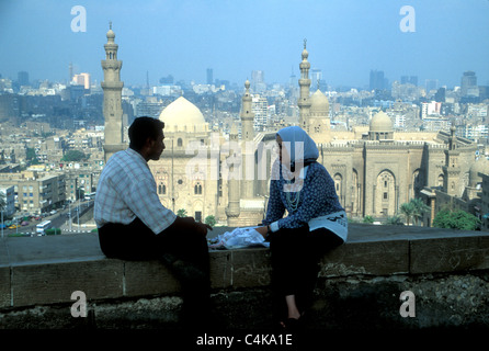 Junge und Mädchen auf einer Wand mit Blick auf Kairo von der Zitadelle mit Hassan Moschee unten sitzen,. Stockfoto