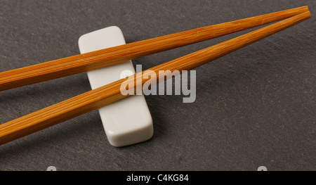 Sitzen auf weiße Stäbchen ruhen auf einem Schiefer Tischset Stockfoto