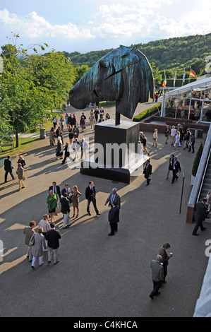 Racegoers in Goodwood Pferderennbahn Treffen am Abend im Juni mit riesigen Pferd Skulptur Stockfoto