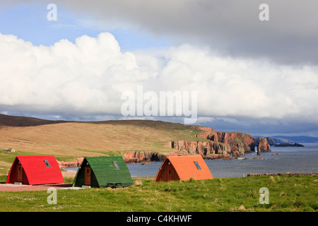 Eshaness, Shetland Islands, Schottland, Großbritannien. Hölzerne Wigwams im Braewick Café Campingplatz mit Blick auf das Meer und die zerklüftete Küste Stockfoto