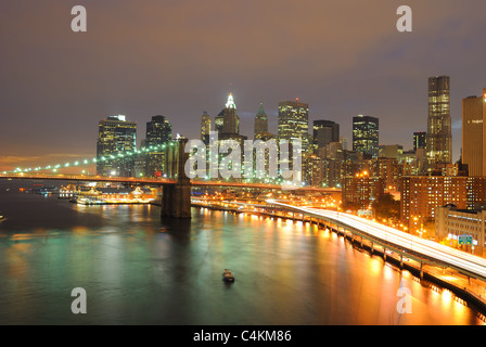 Skyline von Manhattan und Brooklyn Bridge mit untergehende Sonne dahinter. Stockfoto