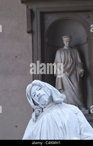 Ein MIME-Straßenkünstler stehen vor einer Statue von Cosimo Pater Patriae, eine der vielen Statuen außerhalb der Uffizien. Stockfoto