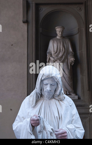 Ein MIME-Straßenkünstler stehen vor einer Statue von Cosimo Pater Patriae, eine der vielen Statuen außerhalb der Uffizien. Stockfoto