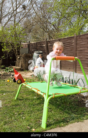 Kleine Mädchen Kleinkind springen hoch Trampolin im Garten Stockfoto