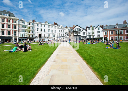 Das Grün der Kathedrale von Exeter wo gibt es viele Cafés, Bars und Restaurants mit Menschen entspannen in der Sonne auf dem Rasen. Stockfoto