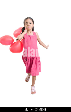 Ein kleines indisches Mädchen gekleidet in rosa laufen mit Luftballons in der Hand. Stockfoto