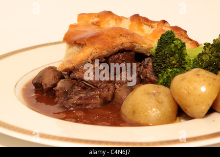 Hausgemachte Steak und Mushroom pie mit einem goldenen Blätterteig Kruste mit gekochten Kartoffeln und Brokkoli portioniert und auf einem Teller serviert. Stockfoto