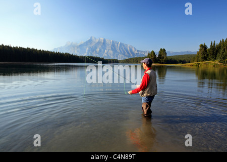 Mittleren Alters männliche Fliege Fischen im Bergsee. Zwei Jack-See mit Rundle Gebirgshintergrund, Banff Nationalpark, Alberta, Canad Stockfoto