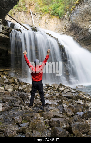 Wanderer vor Wasserfall mit Armen angehoben, Johnson Canyon, Banff Nationalpark, Alberta, Kanada. Stockfoto