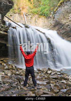 Wanderer vor Wasserfall mit Armen angehoben, Johnson Canyon, Banff Nationalpark, Alberta, Kanada. Stockfoto