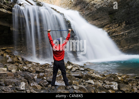 Wanderer vor Wasserfall mit Armen angehoben, Johnson Canyon, Banff Nationalpark, Alberta, Kanada. Stockfoto