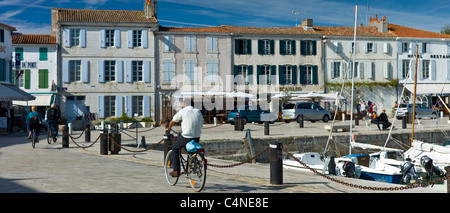 Touristen, die Radfahren entlang des Hafens am Quai de Senac in La Flotte, Ile de Ré, Frankreich Stockfoto