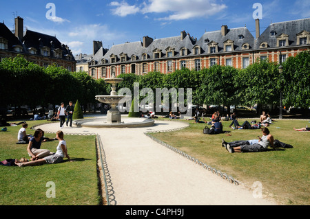 Leute sitzen in der Sonne in Place des Vosges in Paris Stockfoto