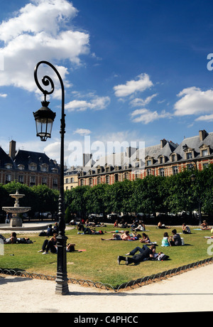 Leute sitzen in der Sonne in Place des Vosges in Paris Stockfoto
