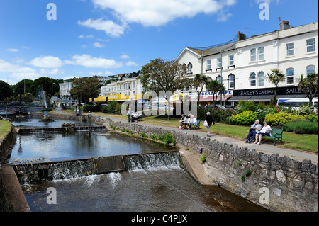 Bewohner und Touristen nehmen Sie am Flussufer im Rasen Park Bereich Dawlish Devon England Vereinigtes Königreich Stockfoto