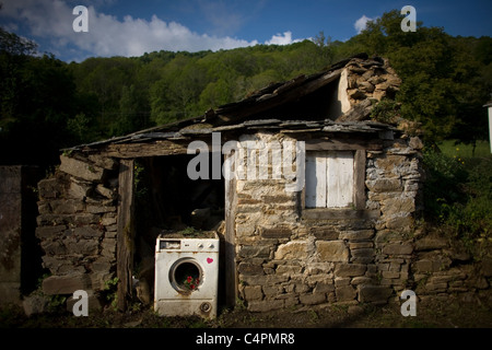 Blumen wachsen im Inneren eine kaputte Waschmaschine blockiert die Tür von einem verlassenen Haus, Französisch Way of St. James Weg, Spanien Stockfoto