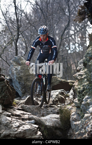 Irische Mountain Bike Champion Robin Seymour reitet auf einen felsigen Pfad durch einen Wald, County Wicklow, Irland Stockfoto