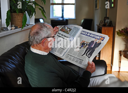 Mann Mitte der Achtziger, der am Sonntag eine nationale Zeitung The Mail auf einem Sofa im Wohnzimmer in Großbritannien las Stockfoto