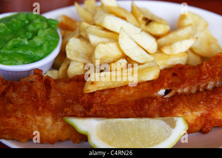 Nahaufnahme einer Platte von Fish &amp; Chips, serviert mit Erbsenpüree und einen Keil von Zitrone. Stockfoto