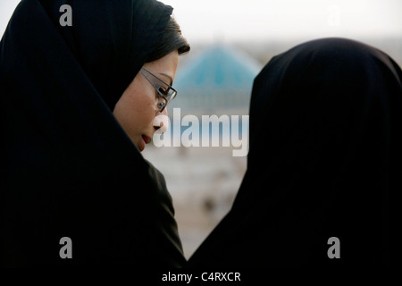 Zwei iranische Frauen, die sich unterhalten, junge Freundinnen in Yazd, Iran. Muslimische Mädchen mit Chador von hinten gesehen Stockfoto