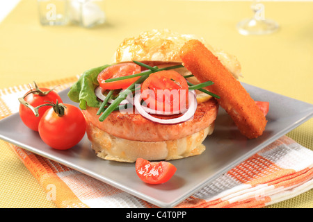 Gebratener Lachs Patty in Käse-Spitze Bun und Gemüsebeilage Stockfoto