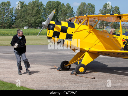 CASA (Bücker) 1-131E3B Jungmann G-TAFF mit Bodenpersonal Propeller schwingen um den Motor zu starten Stockfoto