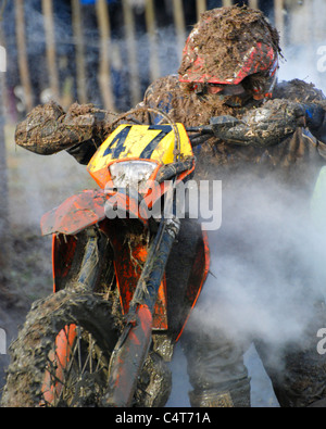 Motorrad Fahrer Fahrrad aus Schlamm schieben, während Enduro-Rennen Stockfoto