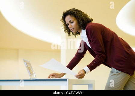 Geschäftsfrau mit Laptop-Computer und im Dokument suchen Stockfoto