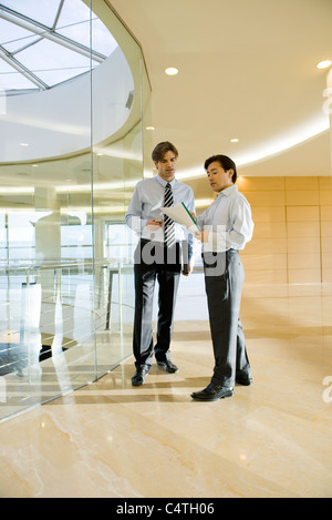 Unternehmer diskutieren Dokument im Korridor Stockfoto