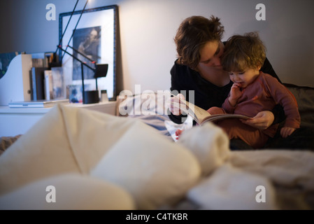 Mutter mit Kleinkind Sohn auf Schoß, Gutenachtgeschichte im Bett lesen Stockfoto