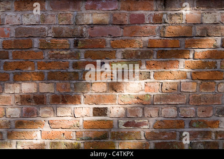 Detail der alten roten Backsteinmauer mit gefleckten Licht Stockfoto