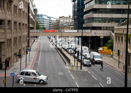 Dem Taxi quer durch London – gebundene morgendlichen Berufsverkehr kommt in die Stadt entlang der unteren Thames Street drehen; A3211. UK Stockfoto