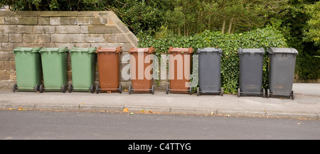 Mülltonnen (grün-braun-grau) für Hausmüll, Recycling & Gartenmüll aufgereiht auf Pflaster zur Sammlung - Leeds, Yorkshire, England, UK. Stockfoto