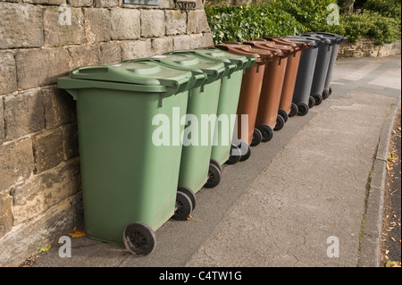 Mülltonnen (grün-braun-grau) für Hausmüll, Recycling & Gartenmüll aufgereiht auf Pflaster zur Sammlung - Leeds, Yorkshire, England, UK. Stockfoto