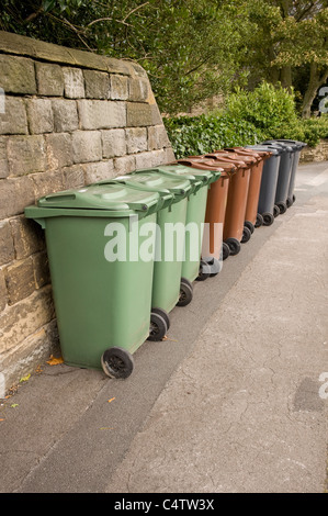 Mülltonnen (grün-braun-grau) für Hausmüll, Recycling & Gartenmüll aufgereiht auf Pflaster zur Sammlung - Leeds, Yorkshire, England, UK. Stockfoto