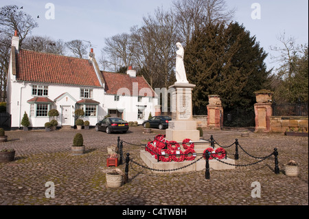 Rote Mohnkränze, die am Fuße des Kriegsdenkmals des 1. Und 2. Weltkriegs in einer attraktiven ländlichen Stadt - Kopfsteinpflaster Hall Square, Boroughbridge, North Yorkshire, England, Großbritannien, gelegt werden. Stockfoto