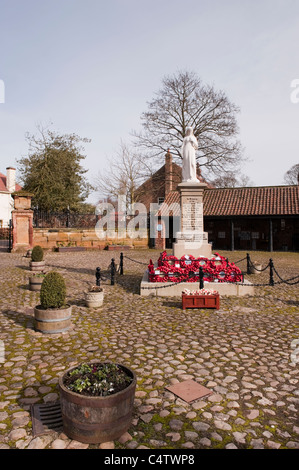 Rote Mohnkränze, die am Fuße des Kriegsdenkmals des 1. Und 2. Weltkriegs in einer attraktiven ländlichen Stadt - Kopfsteinpflaster Hall Square, Boroughbridge, North Yorkshire, England, Großbritannien, gelegt werden. Stockfoto