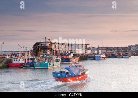 Bridlington bei Sonnenuntergang (Fischerboot kommt in den Hafen, Boote am Pier, Fischkai, ruhiges Meer) - malerische North Yorkshire Coast Stadt, England, Großbritannien. Stockfoto