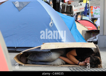 Ein Mann schläft in einem Karton während der wütenden Besetzung der Puerta del Sol in Madrid. Stockfoto