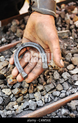 Detail der schmutzigen Hände halten Hufeisen - Schmied Stockfoto