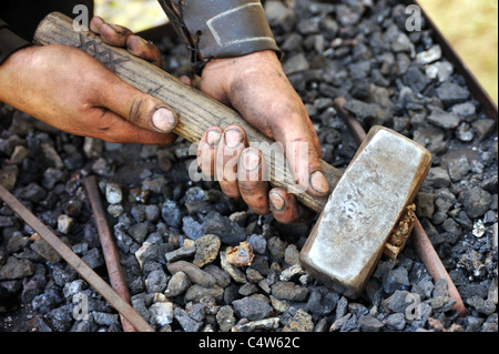 Detail der schmutzigen Hände halten Hammer - Schmied Stockfoto