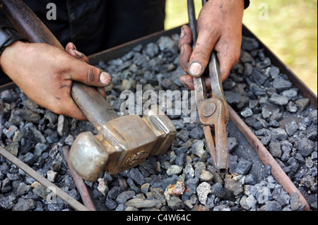 Detail der schmutzigen Hände halten Hammer und Zange - Schmied Stockfoto