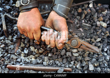 Detail der schmutzigen Hände halten Zange - Schmied Stockfoto